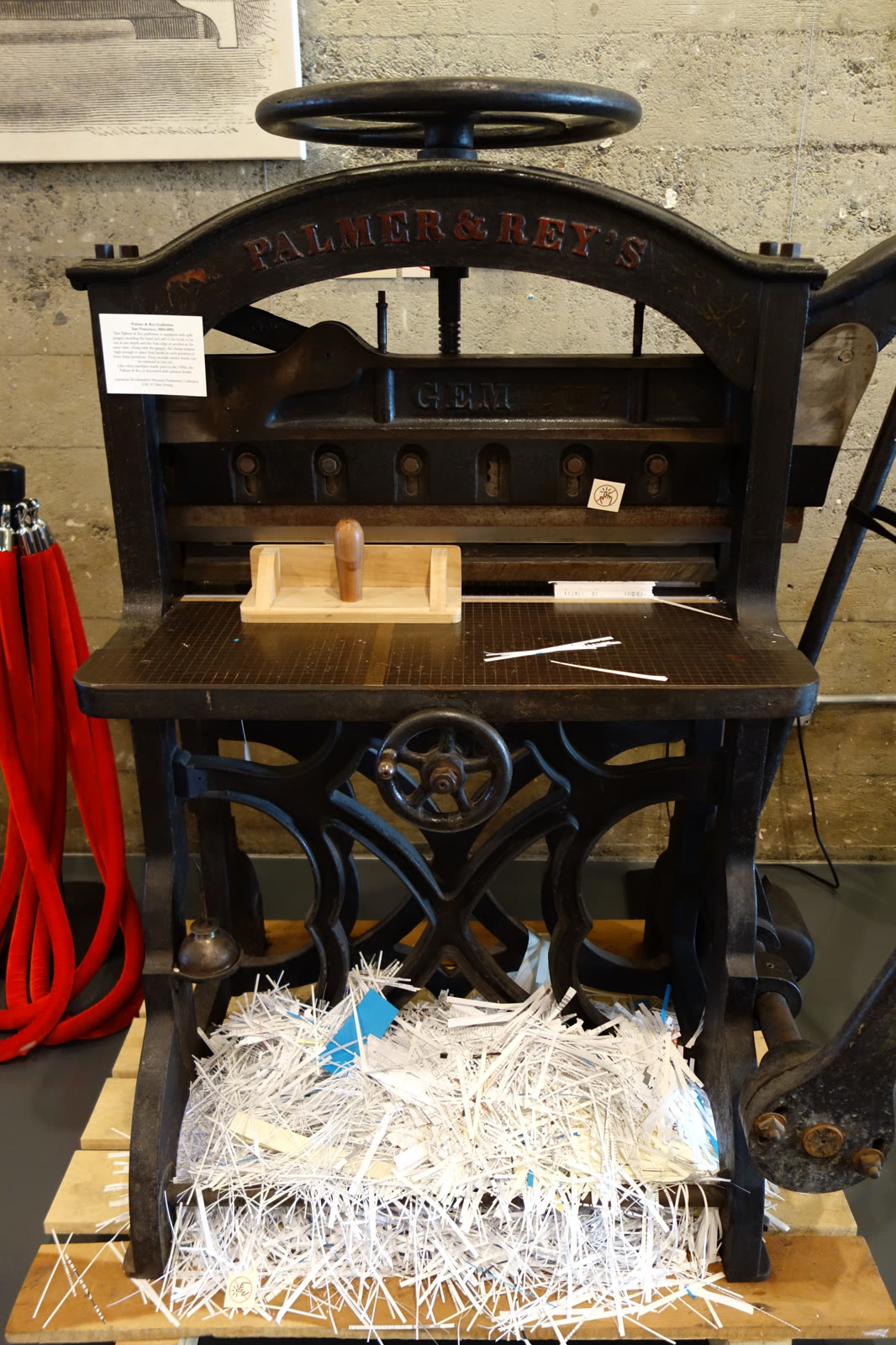 Guilhotina de papel antiga com aparas de papel embaixo